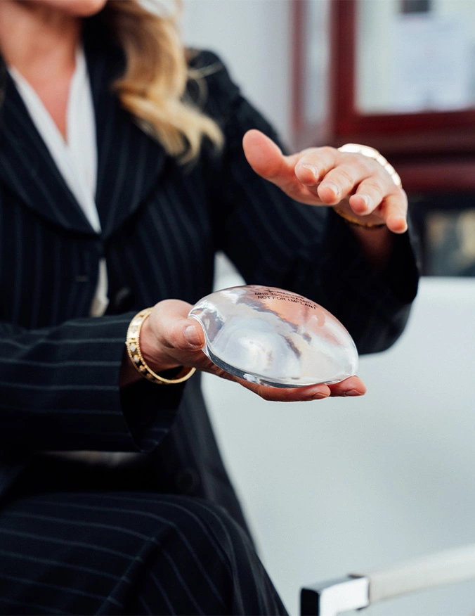 Professional woman in pinstripe suit holding transparent crystal ball in office setting - Breast augmentation with lift in Newport Beach, CA
