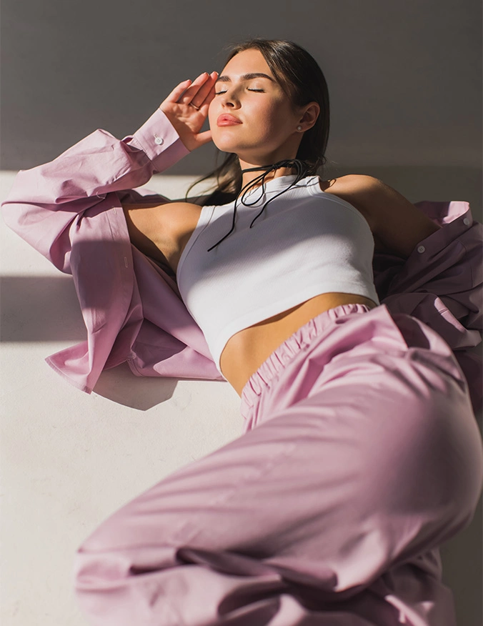 Woman in purple tracksuit and white crop top relaxing in modern athletic wear outfit - Breast implant illness in Newport Beach, CA