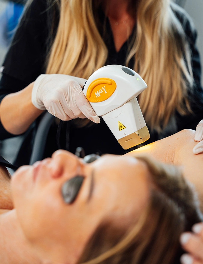 Aesthetician applying golden honey wax to client's face during facial hair removal treatment at spa - laser skin treatment in Newport Beach, CA