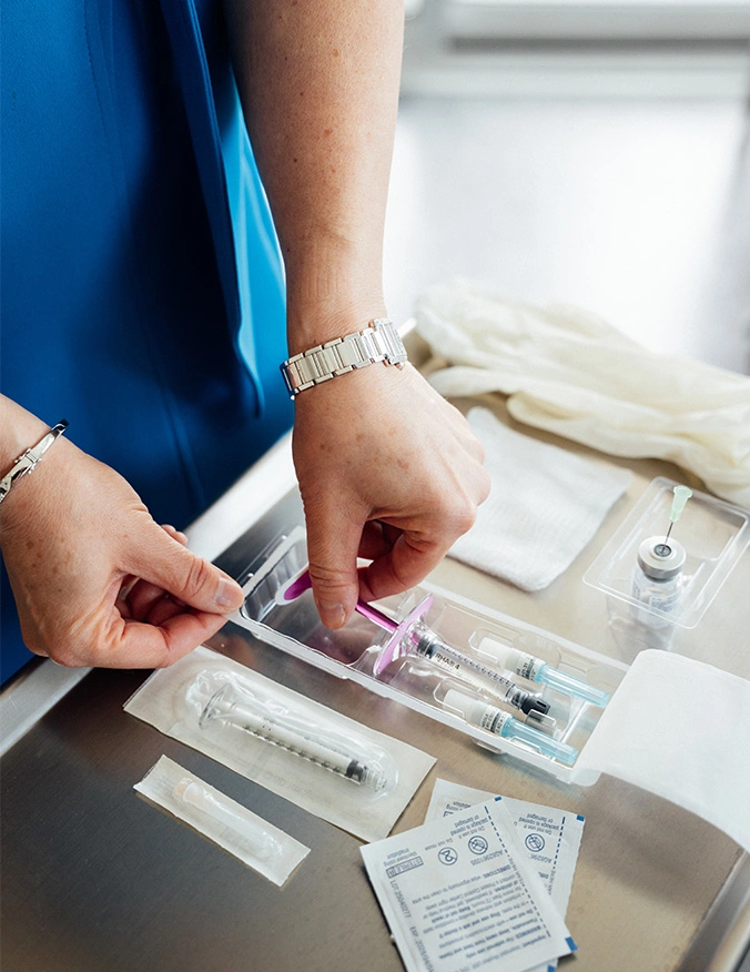 Woman organizing wedding invitation suite with envelope, RSVP card, and decorative elements on white table - Lip fillers in Newport Beach, CA