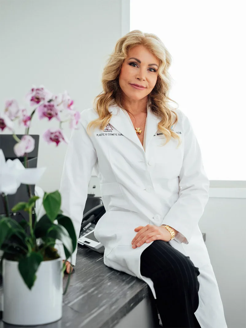 Doctor Bayati in white medical coat sitting confidently in modern clinical office with orchid plant