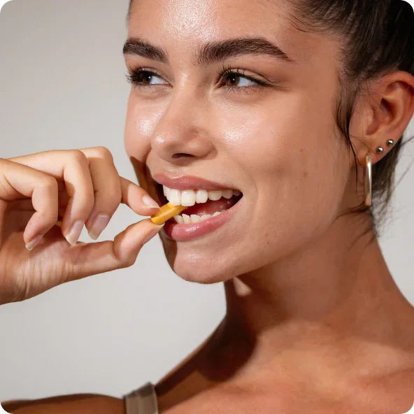 Woman smiling while brushing teeth with natural wooden toothbrush for eco-friendly oral care routine - wellness Biote in Newport Beach, CA