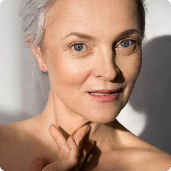 Mature woman with gray hair and natural beauty touching face, showing healthy glowing skin and confident smile - wellness hormone therapy in Newport Beach, CA