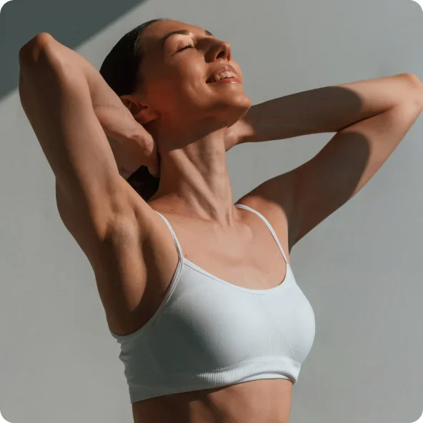 Woman stretching in white sports bra with hands behind head, demonstrating fitness and wellness pose - welness peptides in Newport Beach, CA