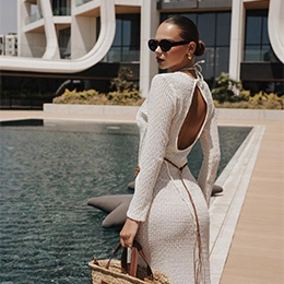 Woman in elegant white backless dress with sunglasses posing by luxury pool at modern resort - Butt lift in Newport Beach, CA